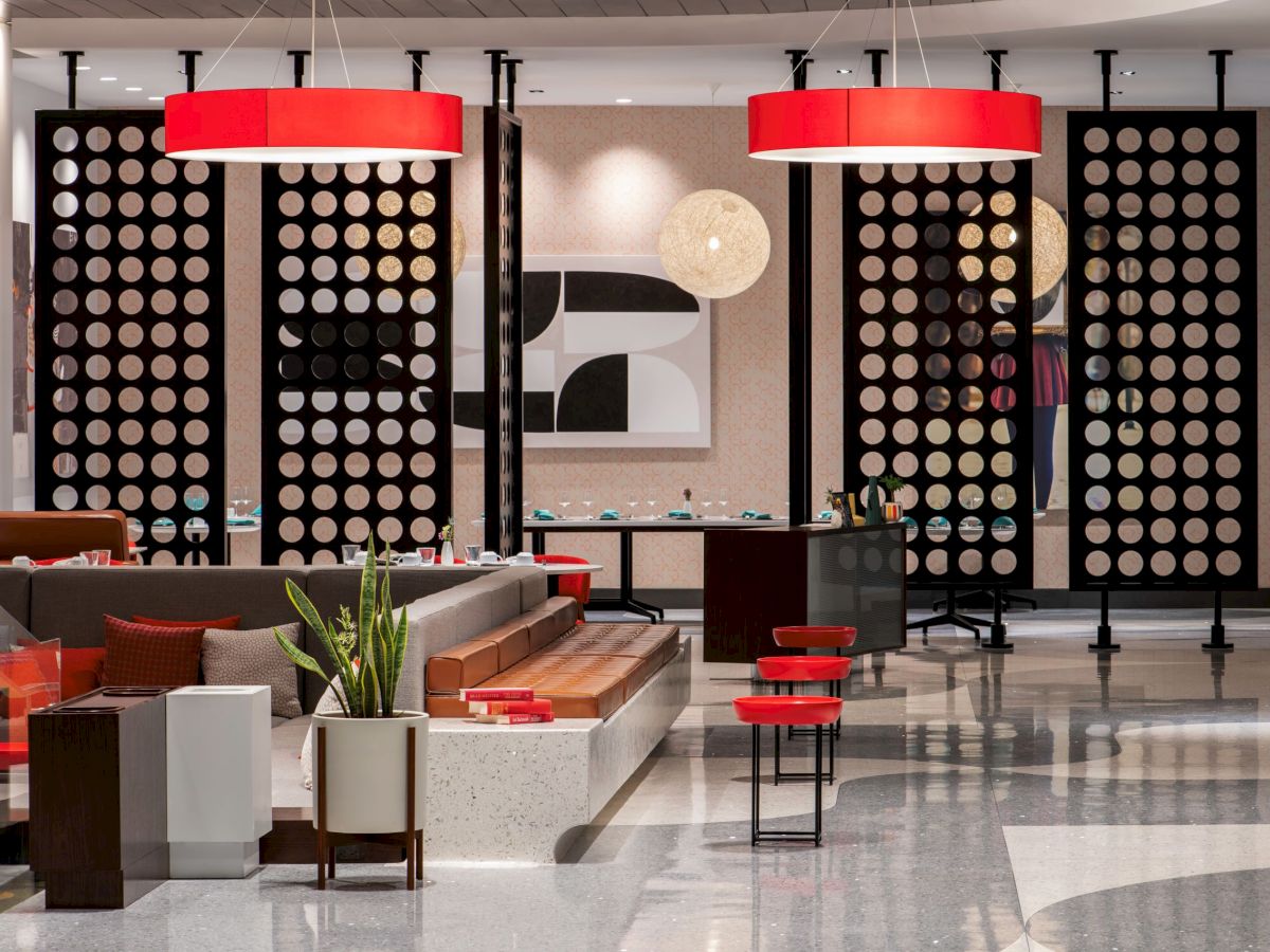 A modern lobby with circular partitions, red accents, stylish seating, and contemporary decor creates a welcoming atmosphere.