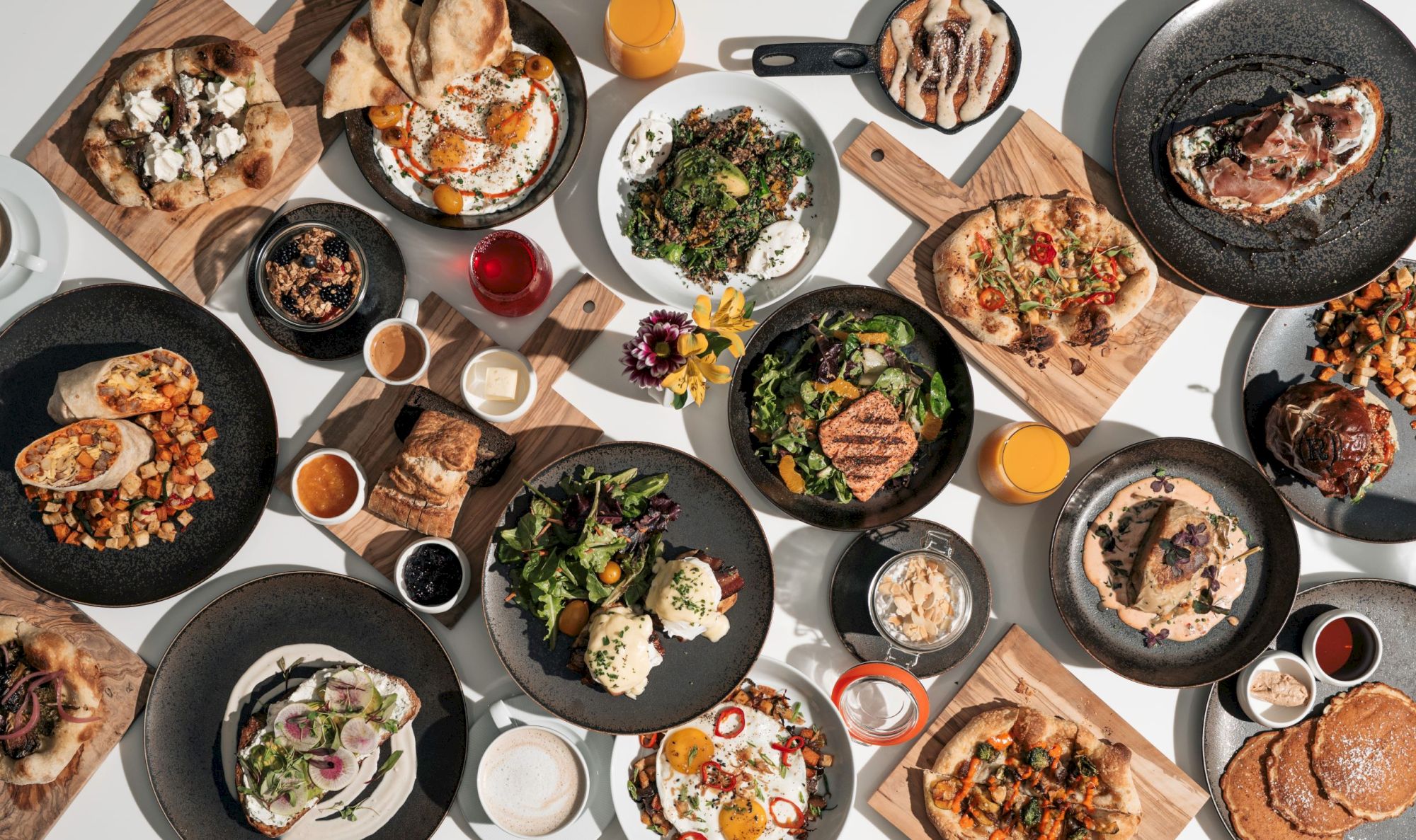 A variety of dishes including salads, meats, and breads arranged on a table with drinks and sauces.